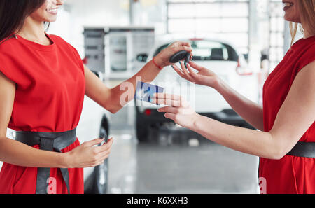 Lächelnd Autoverkäufer Übergabe ihres neuen Autoschlüssel, Ho und Vertriebskonzept. Happy girl der Käufer. Stockfoto