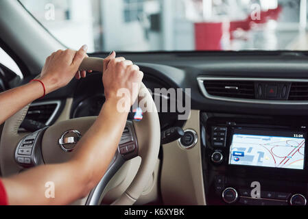 Frau in dem Auto innen hält Rad drehen um ein Lächeln auf die Passagiere im Fond Idee Taxifahrer gegen Sonnenuntergang strahlen Licht himmel Konzept suchen Stockfoto