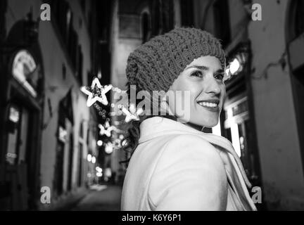 Reise voller Inspiration in der Weihnachtszeit in Florenz. lächelnde moderne Frau Spaziergang durch geheimnisvolle Straßen von Weihnachten Florenz, Italien Stockfoto