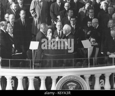Lyndon Baines Johnson nimmt den Amtseid als Präsident der Vereinigten Staaten von Chief Justice Earl Warren am 20. Januar 1965, im Capitol. Nur über themn sind Frau Johnson und Vizepräsident Hubert H. Humphrey. Washington, DC. 1965. Stockfoto