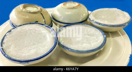 Traditionelle thailändische süße Nachspeise: Kanom Tuay, Kokosmilch Pudding in kleinen Porzellan Tassen. Fokus auf der Vorderseite. Stockfoto