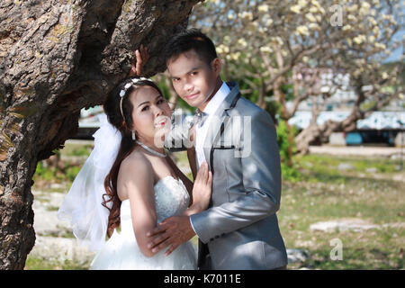 Foto von Vor Hochzeit Asiatische Paare unter einem Baum in einem Blumengarten im Konzept der Beginn einer Partnerschaft leben und Familie. Stockfoto