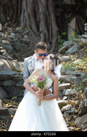 Foto von Vor Hochzeit Asiatische Paare unter einem Baum in einem Blumengarten im Konzept der Beginn einer Partnerschaft leben und Familie. Stockfoto