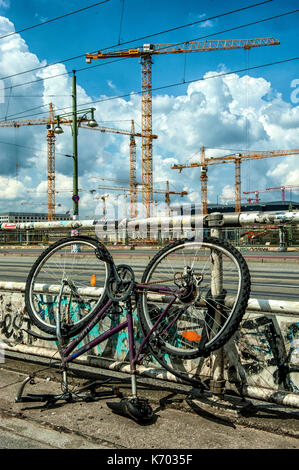 Deutschlands Berlin Warschauer Strasse: ein Fahrrad nach oben Seite nach unten in den Bürgersteig und Kräne an der Arbeit im Hintergrund geparkt Stockfoto