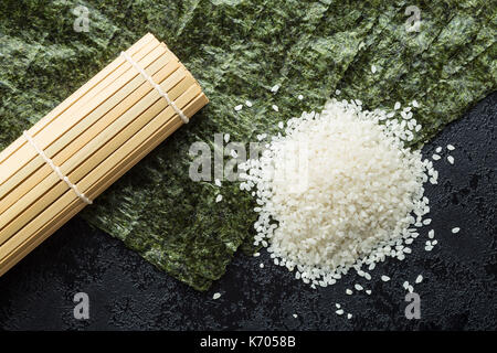 Grüne nori Blatt, Reis und Bambus Matte auf Schwarzen Tisch. Ansicht von oben. Stockfoto