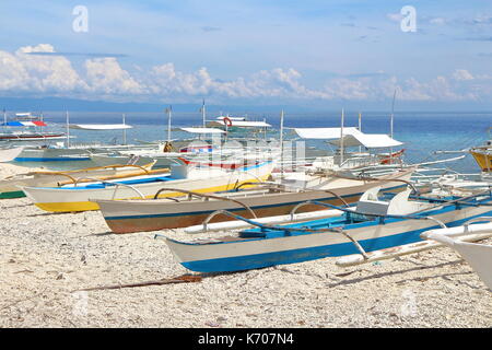 Eine Gruppe von kleinen Kanu Boote angedockt im weißen Sand Küsten der tropischen Insel Panglao auf den Philippinen. Foto auf einem hellen, sonnigen Tag genommen. Stockfoto