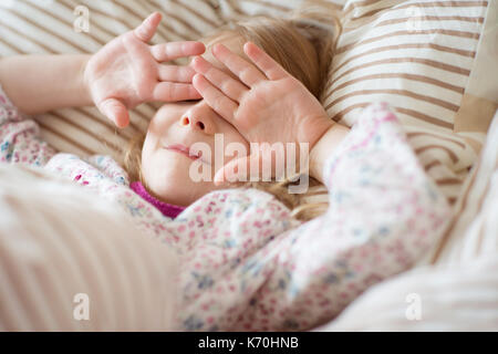 Hübsches kleines Mädchen spielte nach dem Aufwachen am Morgen in ihrem Bett Stockfoto