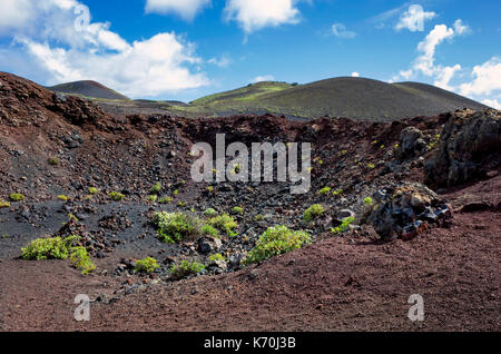 Los Volcanes de Teneguía, Fuencaliente, La Palma. Ein Blick auf die karge Landschaft in den Krater eines der kleinen Vulkane. Auch hier, einige Vegetation wächst auf dem trockenen Land mit dem eigentlichen Krater dieser rauen Umgebung. Es ist ein heller Tag mit trüben Sonnenschein und ein paar Regenwolken. Stockfoto