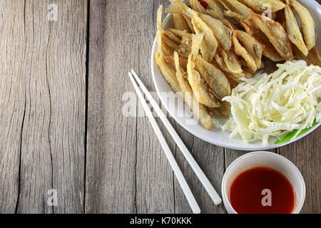 Silber ANCISTRUS oder Sillaginidae Fische gebraten in Teller auf Holzboden dieses einem lokalen Thai Lebensmittel in beliebt. Stockfoto