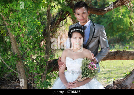 Foto von Vor Hochzeit Asiatische Paare unter einem Baum in einem Blumengarten im Konzept der Beginn einer Partnerschaft leben und Familie. Stockfoto