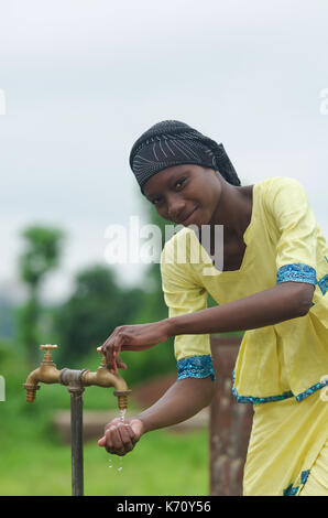 Junge schöne Afrikanische Mädchen im Freien halten sich an den Händen unter Wasser Leitungswasser Symbol für afrikanische Frauen Stockfoto