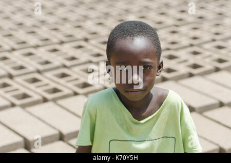 Die Ausbeutung von Kindern Symbol - African Black Boy mit Losen Ziegel hinter ihm - Afrikanische Kinder Arbeit Arbeit Stockfoto