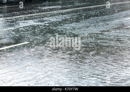 Regentropfen auf Asphalt mit Wasserwellen bei starkem Regen Stockfoto