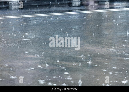 Regentropfen auf Stadt Asphaltstraße bei Regenwetter Stockfoto