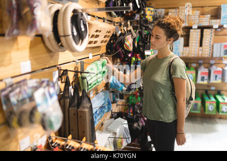 Junge Frau Prüfung Sportgeräte in Store Stockfoto