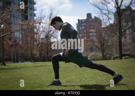 Volle Länge des jungen Mannes Ausübung auf Feld gegen Gebäude Stockfoto