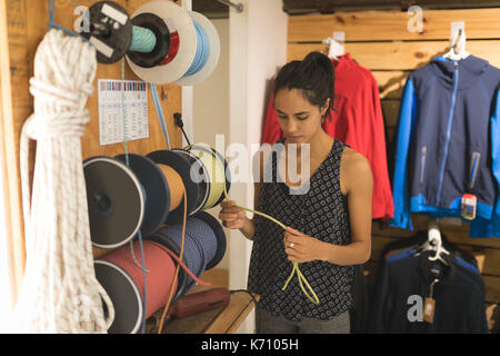 Junge Frau Prüfung Kletterseile in Store Stockfoto