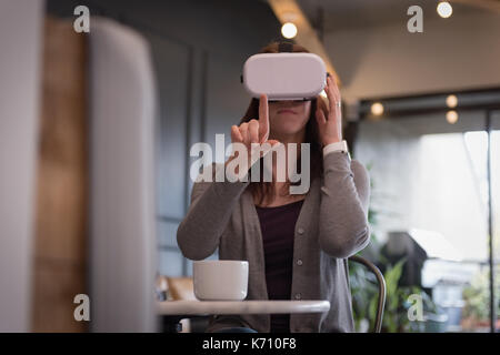 Geschäftsfrau tragen virtual reality Simulator am Tisch im Büro Stockfoto