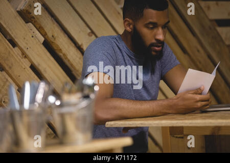 Junger Mann lesen Papier beim Sitzen im Cafe Stockfoto