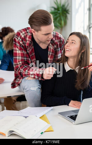 Zwei fröhliche tausendjährigen Studenten lachen, während sitzen zusammen Stockfoto