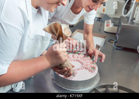 Konditor Frauen setzen Sie die Creme auf die Kuchen Stockfoto