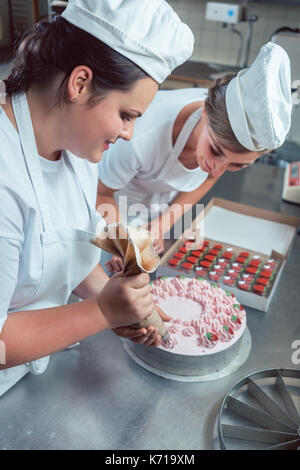 Konditor Frauen setzen Sie die Creme auf die Kuchen Stockfoto