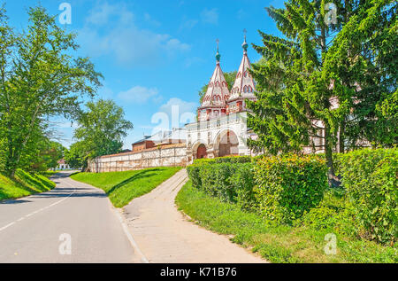 Der Blick durch die üppigen Tannen auf den Heiligen Pforten der Rizopolozhensky Kloster (Ablagerung von der Robe), dekoriert mit zwei Türmen und farbigen Patte Stockfoto