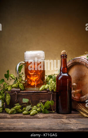 Stillleben-Komposition mit Holzfass, Glas und Flasche frisches Bier Stockfoto