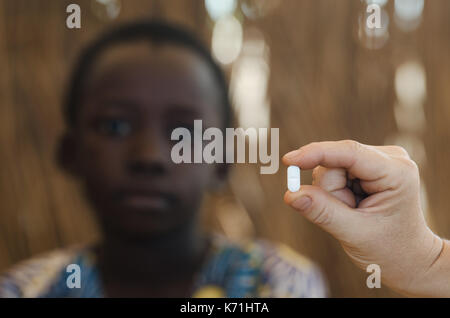 Die jungen afrikanischen Jungen, eine Medizin Pille von einem weißen Arzt Stockfoto