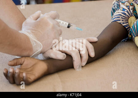 Freiwilliges Engagement für afrikanische Kinder - Weiße Krankenschwester gibt Injektion zu schwarzen Jungen Stockfoto
