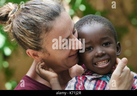 Porträt der europäischen Frau mit einem schwarzen afrikanischen Jungen Stockfoto