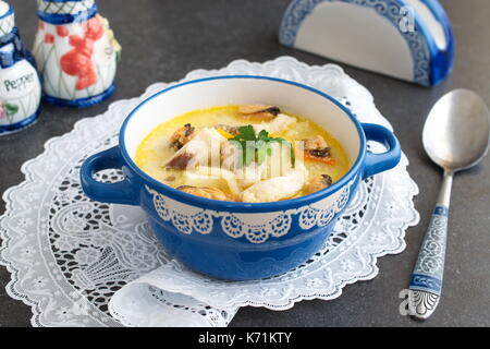 Cremige Suppe mit Fischfilet und Muscheln in einem blauen Keramik Topf auf einem weißen Tuch an einem grauen Abstrakt Hintergrund. Gesunde Ernährung Konzept. Mediterranen Lebensstil Stockfoto