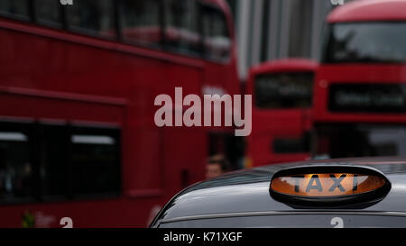 Nahaufnahme der Taxi Schild auf einem traditionellen Londn cab mit roten Doppeldecker im Hintergrund in den Straßen von London, Großbritannien Stockfoto