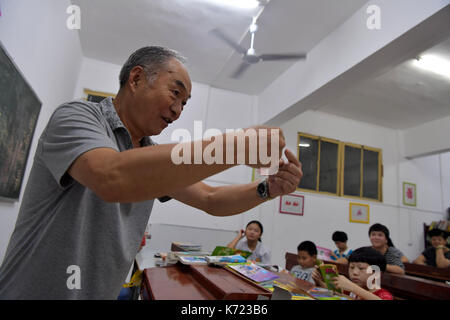 (170914) - NANCHANG, Sept. 14, 2017 (Xinhua) - Er Xingwu erzählt Geschichten mit Gebärdensprache in einer speziellen Schule in Nanchang, der ostchinesischen Provinz Jiangxi, Sept. 13, 2017. Der 74-jährige Lehrer er Xingwu hat in den Speical Schule für 23 Jahre gearbeitet. Er verlor die Anhörung im Alter von acht Jahren durch die missbräuchliche Verwendung von Drogen. 1994, er und sein Freund gegründet, um die Schule nach seinem Ruhestand. Mehr als 300 Anhörung-und-sprechenden sehbehinderte Schüler haben von der Schule absolvierte. (Xinhua / Peng Zhaozhi) (zkr) (ZT) Stockfoto
