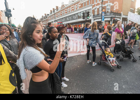 London, Großbritannien. 14. September 2017. Menschen waqtch und Fotografien als Mitkämpfer aus dem Stand nach oben Töten Londonern' auf der Überfahrt an BRIXTON U-Bahnhof blockieren die Straße in einem Protest gegen die Londoner übermäßige Luftverschmutzung, vor allem auf den Verkehr. Die Luft auf der Brixton Road Verstöße die Jährliche Umweltbelastung begrenzen in nur 5 Tagen, etwa 70-mal pro Jahr. Giftige Luftverschmutzung führt zu 10.000 vorzeitige Todesfälle in London jedes Jahr und ist besonders schädlich für die Älteren und die ganz Jungen. Auf die Unterbrechung Schnitt zu Verkehr, den Sie von der Straße nach etwa fünf Minuten verschoben Stockfoto