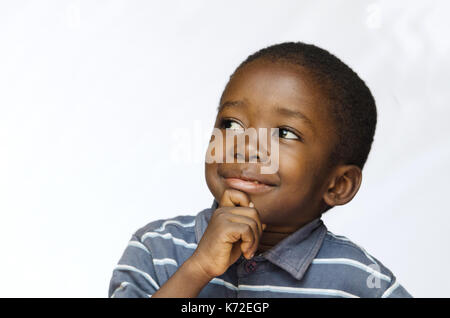 Kleine schwarze Jungen denken mit der Hand am Kinn Stockfoto