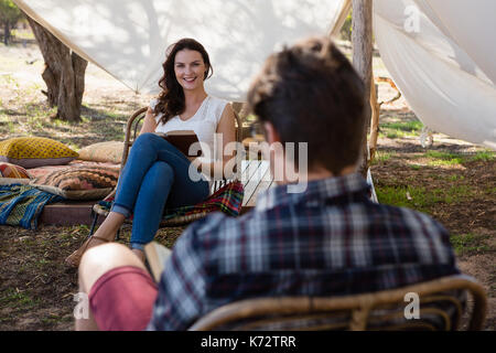 Junge Frau an Mann lesen Buch auf dem Feld Suchen Stockfoto