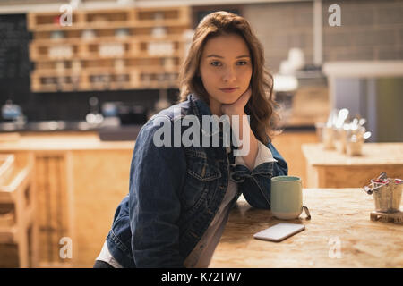 Schöne Frau sitzen in cafÃƒÂ© mit Kaffee auf Tisch Stockfoto