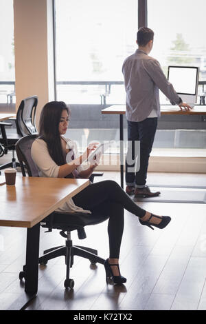Durch Mitarbeiter mit digitalen tablet Geschäftsfrau beim Sitzen auf Stuhl im Büro Stockfoto