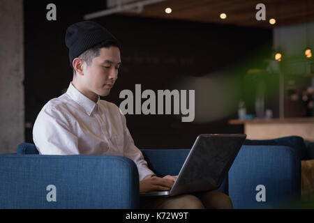Junge Unternehmer mit Laptop auf dem Sessel im Büro Stockfoto
