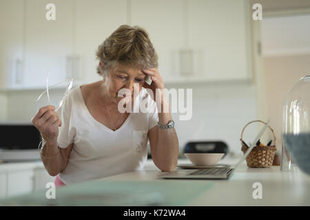 Zeitform senior stehende Frau mit Laptop in der Küche auf die Arbeitsplatte zu Hause Stockfoto