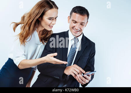 Neugierig Frau in Richtung Bildschirm des Smartphones von Kollegen zeigen Stockfoto