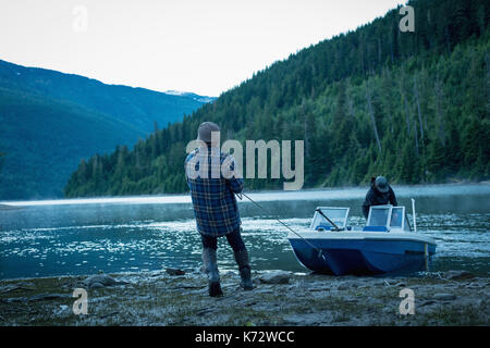 Freunde fahrenden Boot am Flussufer gegen Berg Stockfoto
