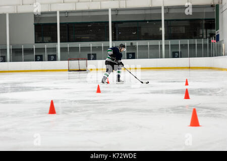 Volle Länge des männlichen Eishockey Spieler üben bohrt mit Eisbahn Stockfoto