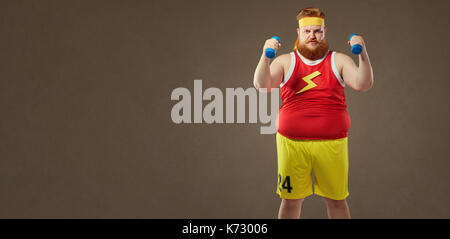 Dicke lustiger Kerl in Sportkleidung mit kleinen Hanteln Stockfoto