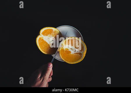 Person schneiden Saft aus frischen Orangen auf hölzernen Tisch zu machen. Das Messer in die Hand schneiden eine saftige orange Stockfoto