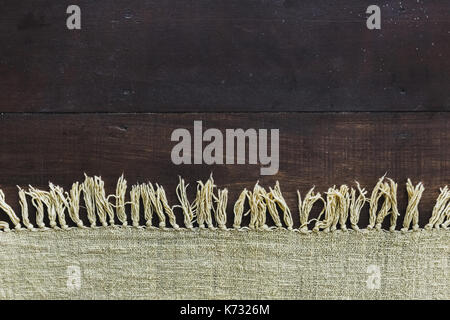 Beige Teppich mit Fransen auf dunkler Holzfußboden, Textur Nahaufnahme Stockfoto