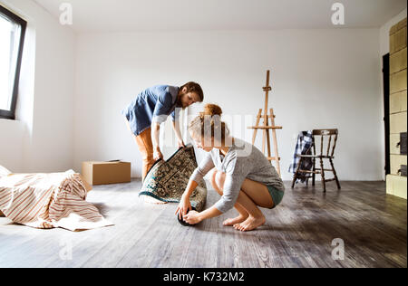 Junges Paar Umzug in neues Haus, heraus rollen Teppich. Stockfoto