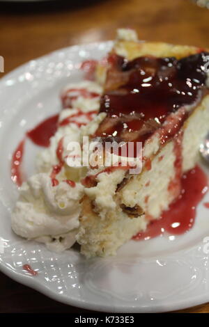 Scheibe der New Yorker Stil, Käsekuchen mit Himbeeren und Sahne Sauce auf einer Platte Stockfoto