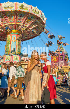 Zwei Mädchen in traditioneller Kleidung fotografieren in Oktoberfest in München, Deutschland Stockfoto